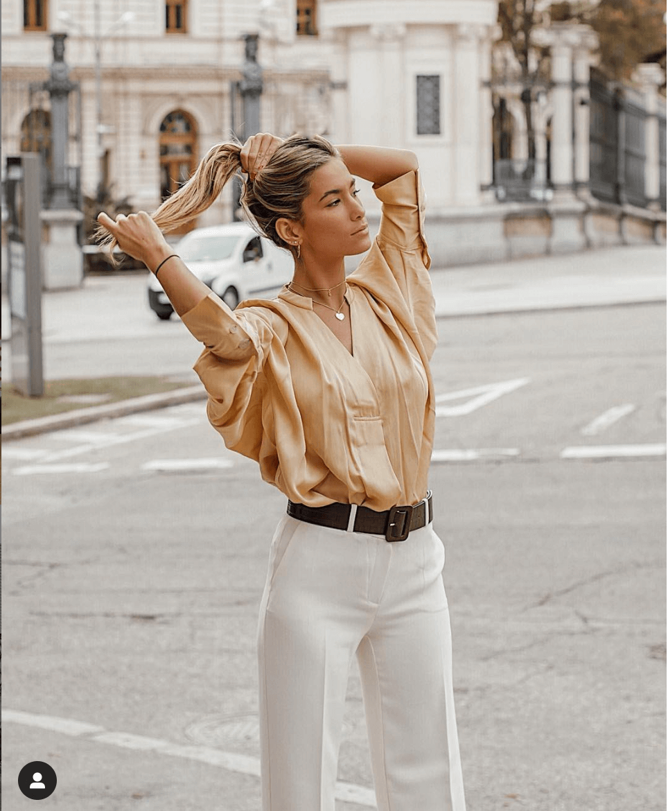 La influencer con un look de pantalón blanco y blusa dorada