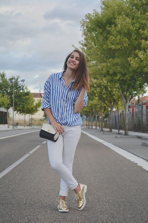 Chica con pantalón blanco y camisa a rayas.