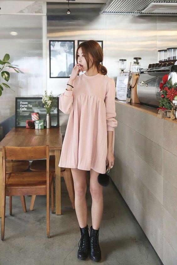 Chica coreana con vestido corto color rosa y botas de combate negras.