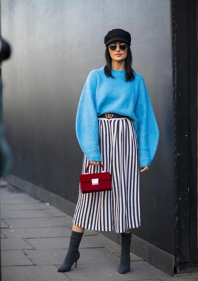 Conjunto de jersey oversize con palones anchos de rayas y bolso rojo.