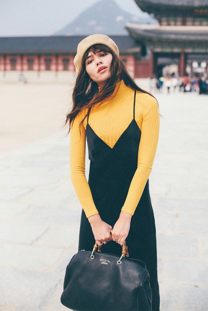 Combinación de vestido negro sobre un jersey amarillo canario.