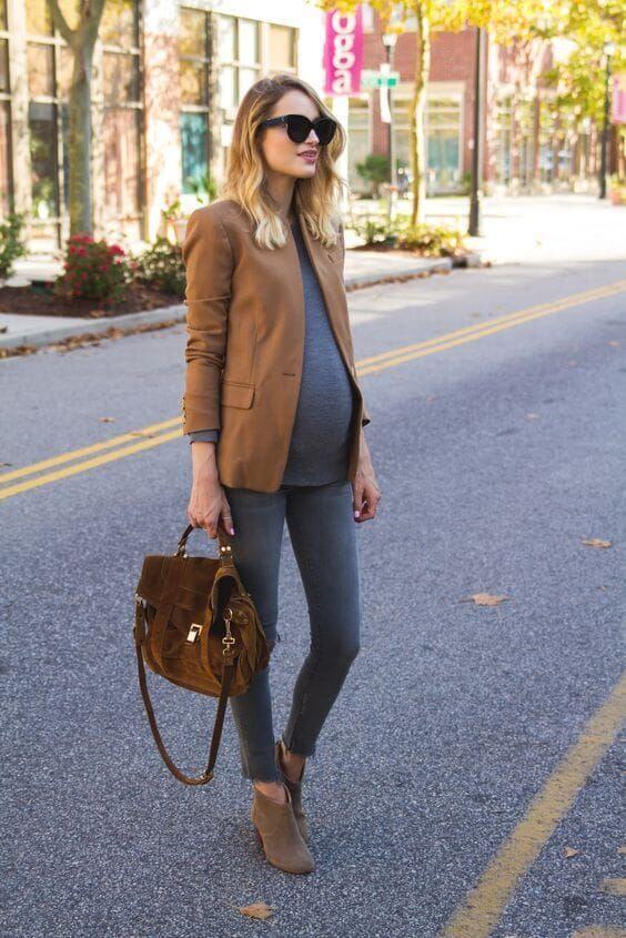 Chica embarazada con jeans, bolso y americana marrón.