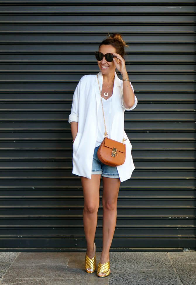 Look de blazer blanca con shorts vaqueros.