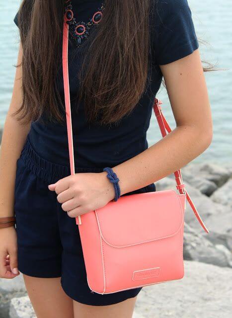 Chica luciendo bolso bandolera en color living coral.