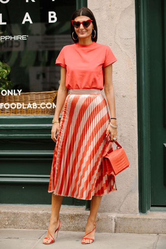 Chica con falda plisada y total look en living coral.